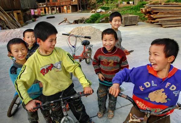 Ragazzi cinesi in sella alle biciclette sui popoli del villaggio etnico di Dong . — Foto Stock