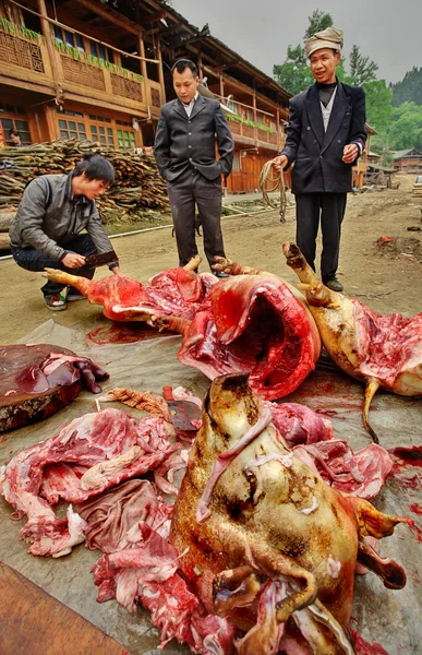 Carniceiros na China rural, camponeses asiáticos agricultores cortam carne de porco . — Fotografia de Stock