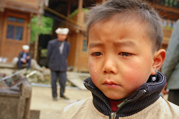 Asian boy 8 years old, is crying in village street.