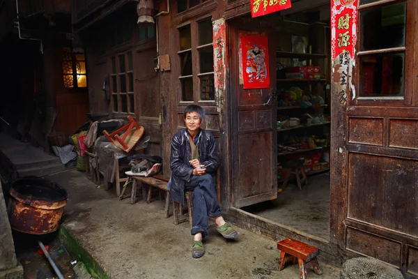 Asiatischer Händler in grünen Turnschuhen sitzt in der Nähe eines Dorfladens. — Stockfoto