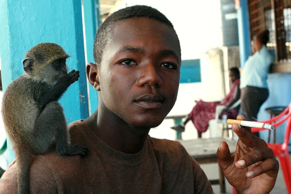 Tame monkey, sits on shoulder of young, black man African. — Stock Photo, Image