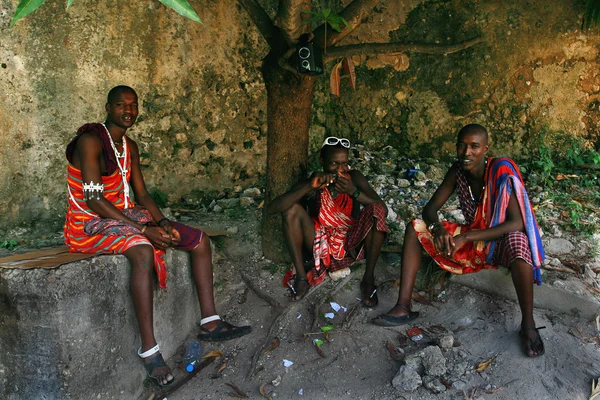 Trois jeunes Africains, vêtements Masaï, se reposent à l'ombre . — Photo