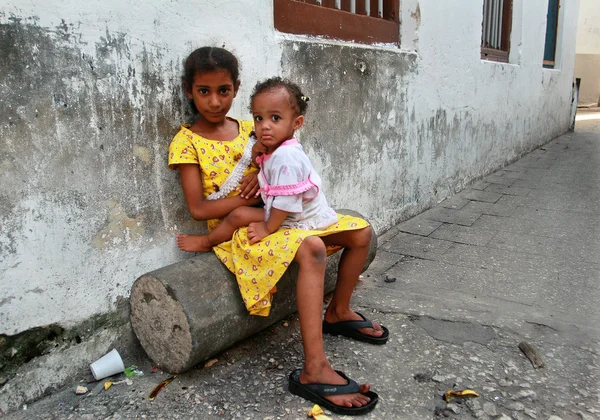 Dark-skinned African girl 8 years old, holds a two-year sister.