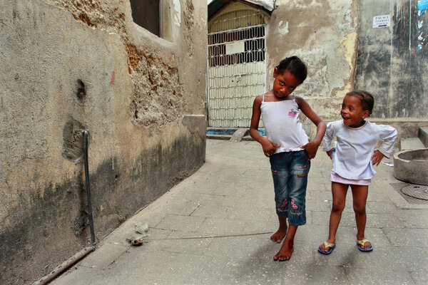 Tanzania, Zanzibar, Stone Town, two dark-skinned girls playing in street.