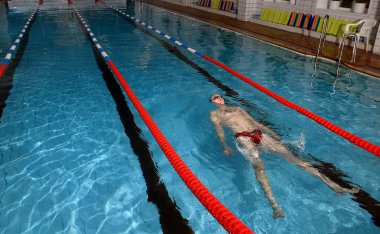 genç adam su üzerinde yatıyor ve yüzme havuzunda rahatlayın.