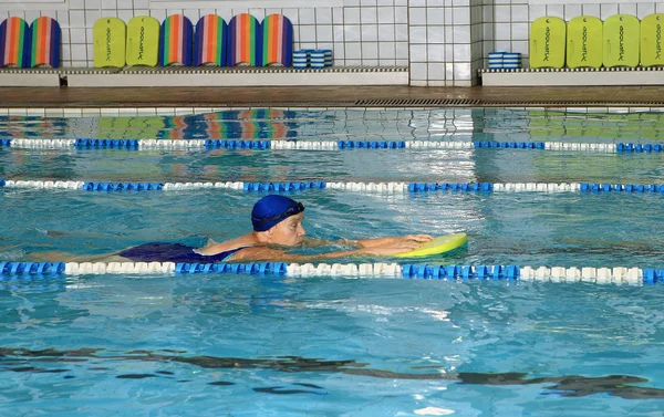 Äldre kvinna simmar i den täckta simhallen. — Stockfoto