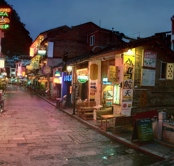 Úzká ulice v noci v malém městečku yangshuo, kavárny, restaurace, hotely. — Stock fotografie