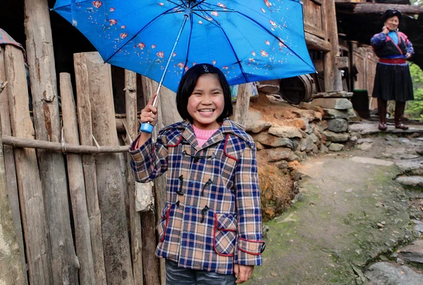 Rural chica asiática, alrededor de 8 años, ocultar paraguas azul y reír —  Fotos de Stock