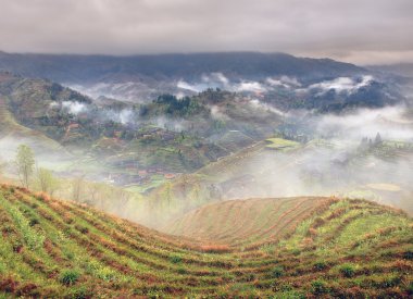 Spring fog in mountains of southwestern China, rice terraces, farmhouses. clipart