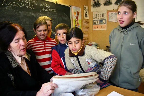 School class in the Russian village school children pupils gathered around a schoolteacher.