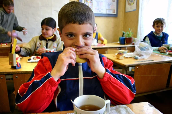 Ora di pranzo in una scuola rurale, lo scolaro pranza mentre è seduto alla scrivania della scuola . — Foto Stock