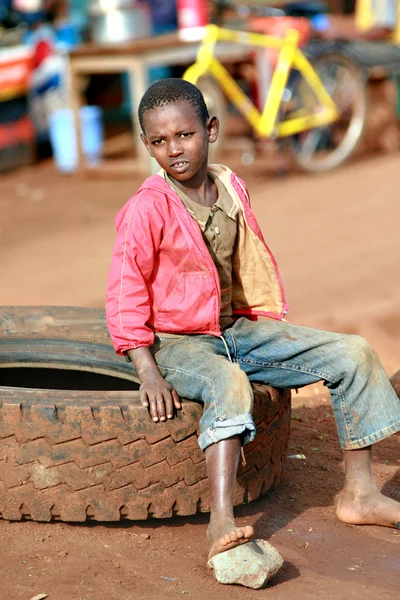 Barefoot black boy, resting, sitting on car tire — Stock Photo, Image