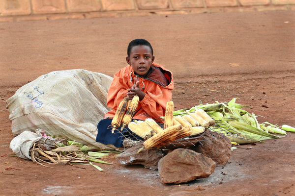 African boy sells corn grill.
