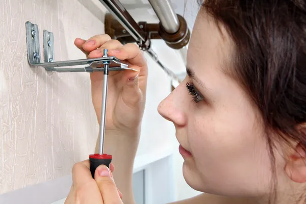 Girl fastens screwdriver bracket vertical blinds to wall. — Stock Photo, Image