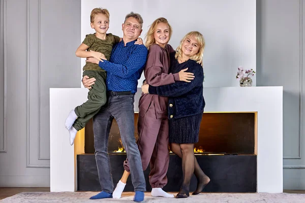 Happy white family stands in living room near fireplace. — Stock Photo, Image