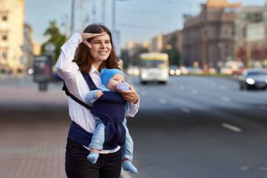 Annesi küçük bir çocukla sokakta trafiğin yanında duruyor..
