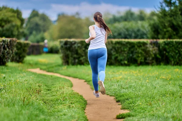 Visão traseira da mulher que está treinando no parque em sportswear. — Fotografia de Stock