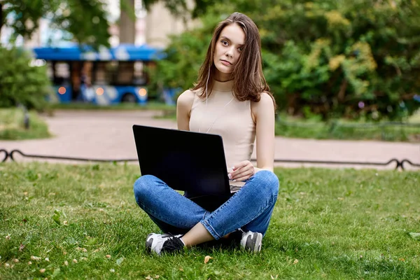 Online-Lernen im Park durch schlanke junge Frau mit Laptop. — Stockfoto