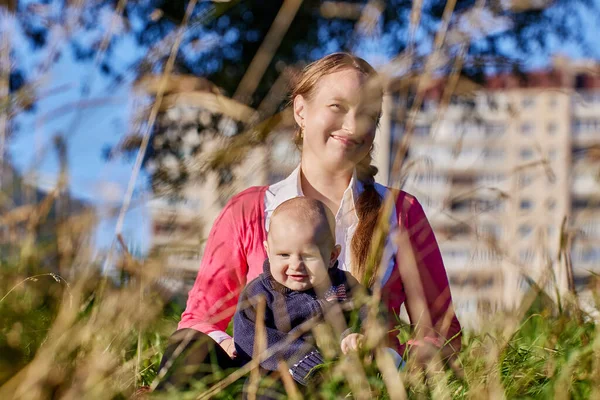 Smiling white woman with baby walks outdoors at daytime. — Stock Photo, Image