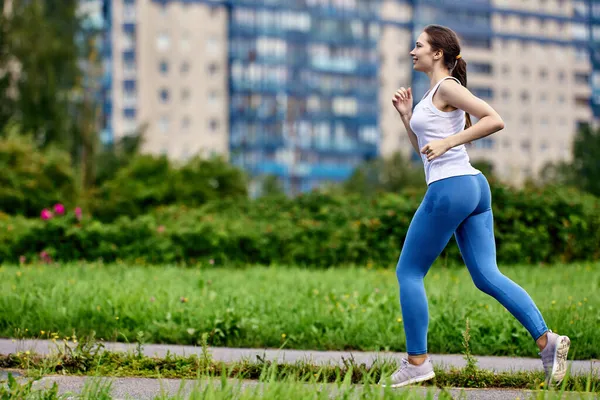 Active young slim woman runs in park in sportswear. — Stock Photo, Image