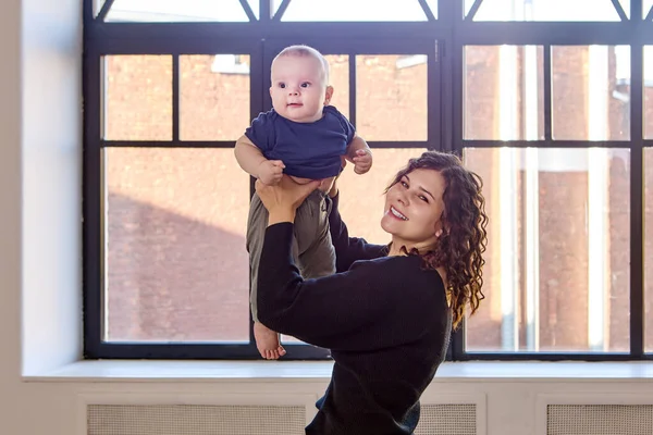 Femme souriante tient le petit garçon dans les mains à l'intérieur. — Photo