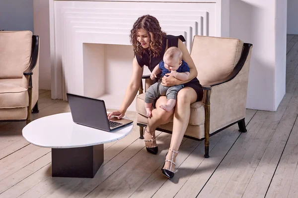 Mère fait du travail à distance avec un ordinateur portable avec bébé à l'intérieur. — Photo