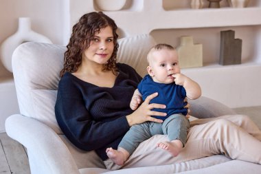 Genç anne kanepede oturuyor. Bebek içeride..
