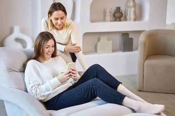 Sœurs Souriantes Sur Canapé Discutent Avec Des Amis Utilisant Smartphone — Photo