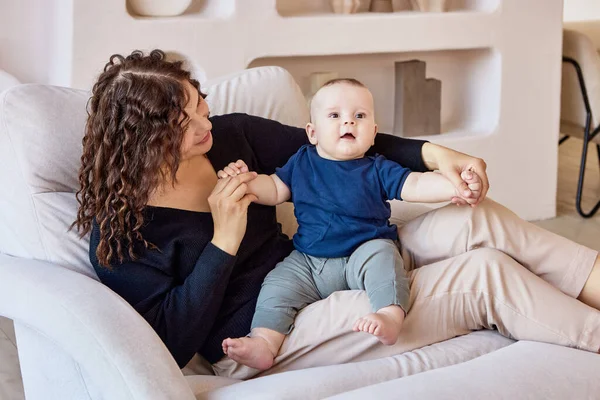 Salon avec jeune mère et bébé assis sur le canapé. — Photo