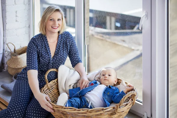 Toddler in basket lies on windowsill with mother near. — Stock Photo, Image