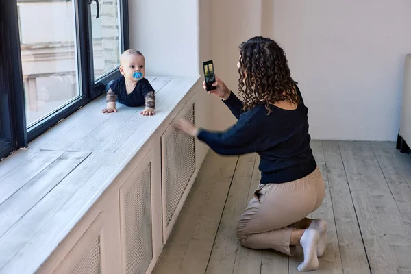 Mère prend une photo du bébé en utilisant un smartphone à l'intérieur. — Photo