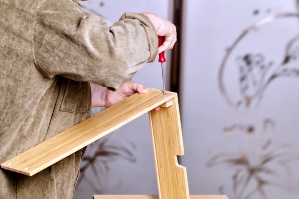 Художник збирає плоскі пакетні меблі за допомогою гвинтів і викрутка. — стокове фото