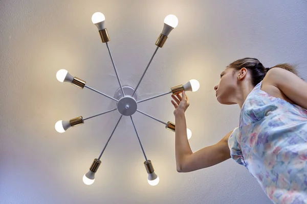 Výměna žárovky v LED lampě za ženu uvnitř. — Stock fotografie
