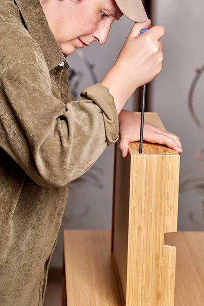 Monteur zieht Schrauben an Schublade von Flachpackmöbeln mit Schraubenzieher an. — Stockfoto