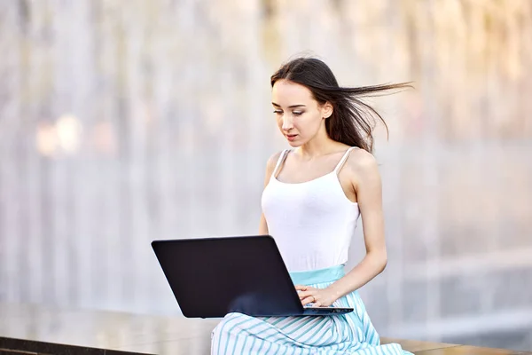 Струнка жінка робить телеобслуговування за допомогою ноутбука на відкритому повітрі . — стокове фото
