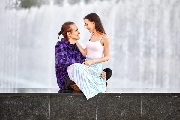 屋外の噴水の近くに座っている若いカップルの日付. — ストック写真