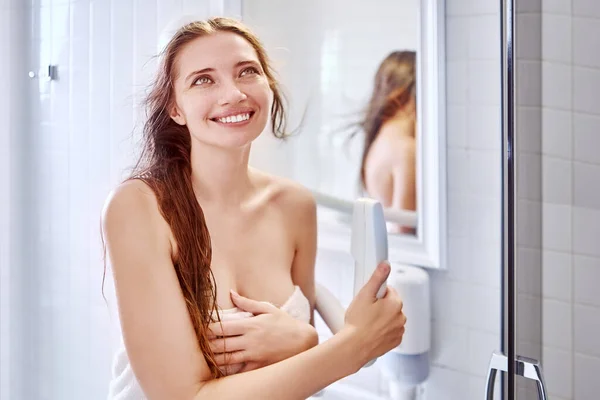 A nő falra szerelt hajszárítót használ a fürdőszobában.. — Stock Fotó