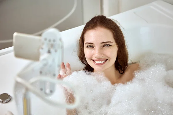 Uchwyt z telefonem przymocowany do kąpieli przez kobietę. — Zdjęcie stockowe