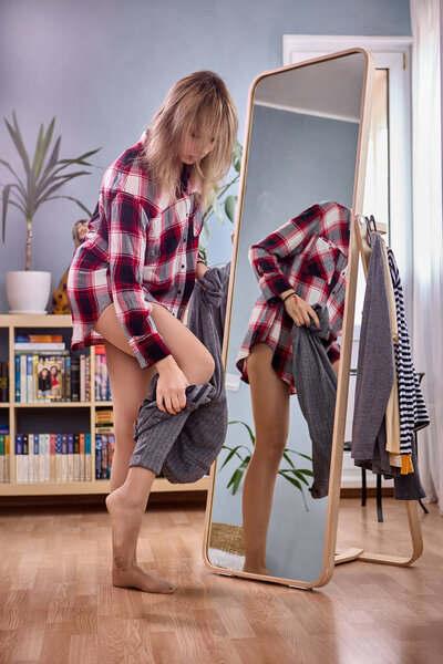 Large full length standing mirror and female changes pants near it.