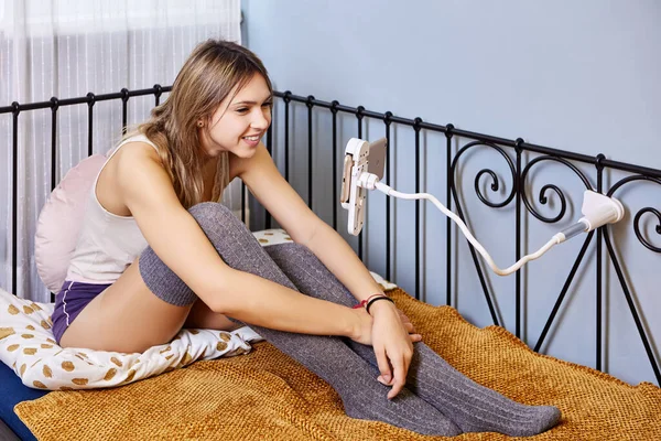 Uchwyt do smartfona przymocowany do łóżka używany przez kobietę oglądającą filmy. — Zdjęcie stockowe