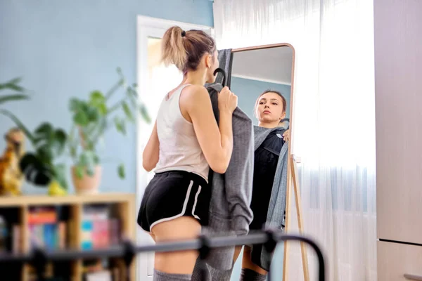 Comprimento total espelho de pé chão e mulher escolhe roupas perto. — Fotografia de Stock