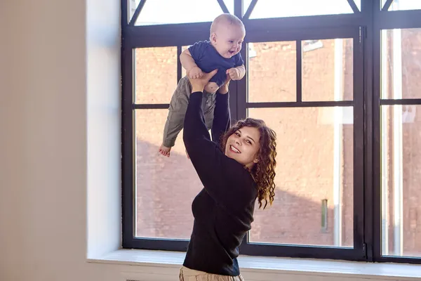 Femme jetant l'enfant devant la fenêtre du salon. — Photo