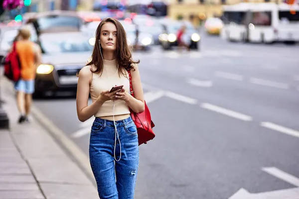 Γυναίκα 18 ετών ακούει μουσική χρησιμοποιώντας smartphone και ακουστικά. — Φωτογραφία Αρχείου
