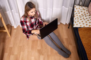 İnternette randevulaşma, dizüstü bilgisayar, ekose gömlek ve çorap giyen kadın internette sevgili arıyor, yatak odasında yerde oturuyor..