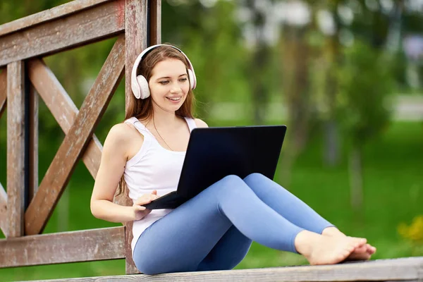 Online lärande eller distansarbete med hjälp av bärbar dator uppkopplat internet via 5g nätverk, ung kvinna gör e-lärande när du besöker offentlig park. — Stockfoto
