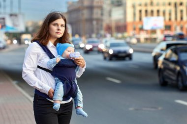Anne yoğun araba trafiğiyle sokakta yürürken, bebek şişesinden içki içen çocuk..
