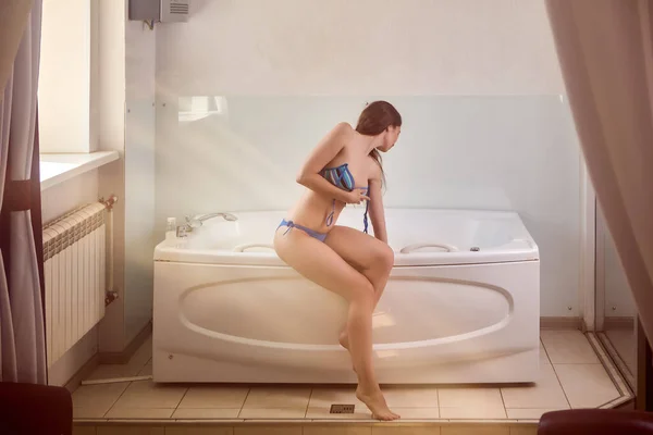 Femme assise sur le bord du bain d'hydromassage chaud et touche l'eau avec sa main. — Photo