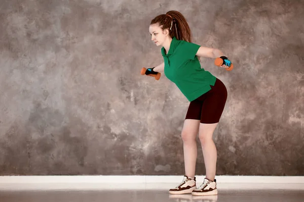 Styrketräning med hantlar på gymmet för den vita kvinnan 28 år. — Stockfoto