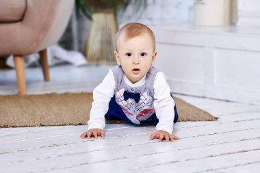 Yürümeye başlayan çocuk, oturma odasının boyanmış döşemesinde dört ayak üstünde sürünüyor..