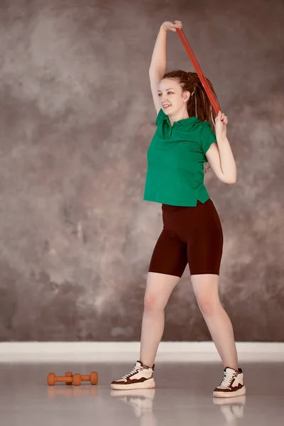 Bande de résistance pour la musculation, jeune femme caucasienne faisant de l'exercice dans la salle de gym. — Photo